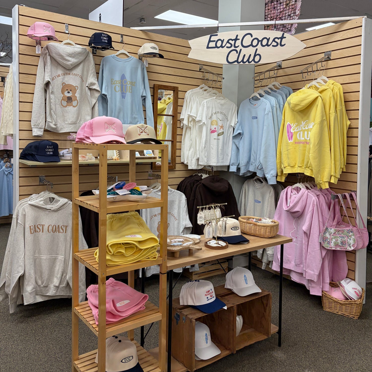 Display of clothing and accessories on a wooden rack with 'East Coast Club' branding.